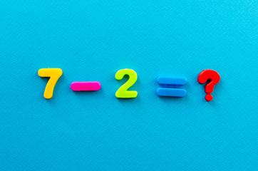 math action from colored plastic numbers on blue paper background