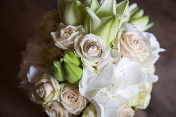 A pair of wedding rings on a bouquet of white flowers, close up shot