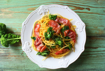 Delicious spicy linguine pasta with fried cabbage kale, bacon, garlic and parmesan on a white plate . Top view
