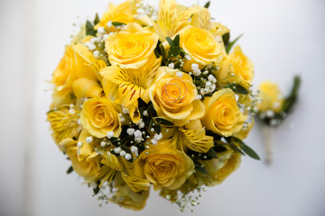 A pair of wedding gold rings on a bouquet of yellow flowers, close up shot