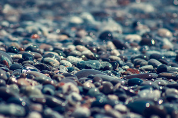 sun reflections on Stones on the beach and sea water in sunset light