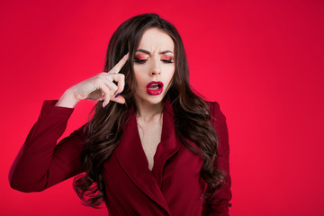 Crazy girl on pink background. Young beautiful woman with bright makeup. The brunette grabbed her head.