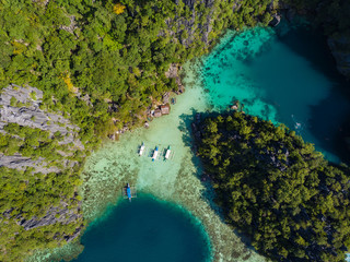 Aerial view to tropical Twin lagoon with azure water and traditional sailing boats, Coron island. Palawan, Philippines.