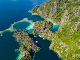 Aerial view to tropical Twin lagoon with azure water and traditional sailing boats, Coron island. Palawan, Philippines.