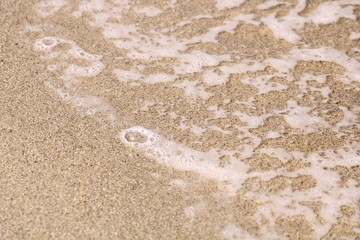 Fototapeta na wymiar Ocean water bubbles on sandy shore in Hopkins, Belize