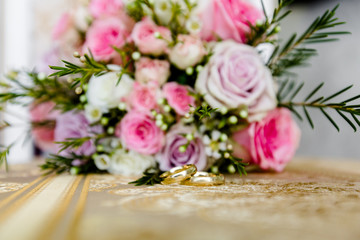Close-up of a pair of wedding rings on the background of a wedding bouquet of flowers