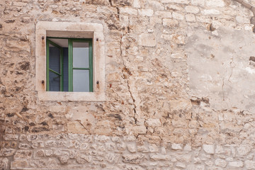 Fototapeta na wymiar Green window on stone wall. Beautiful Mediterranean background. 