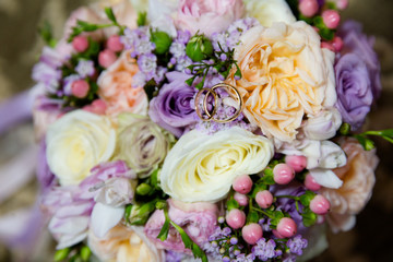 A pair of wedding gold rings on a bouquet of colorful flowers, close up shot