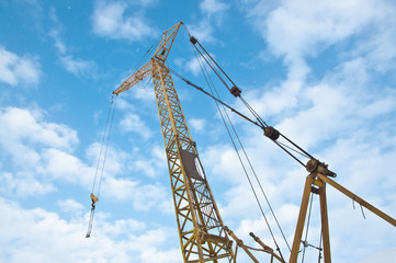 Fototapeta na wymiar Construction crane against the blue sky with clouds. Construction site. Building construction