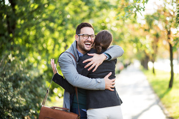 Naklejka na ściany i meble Attractive smiling man hugging woman at park