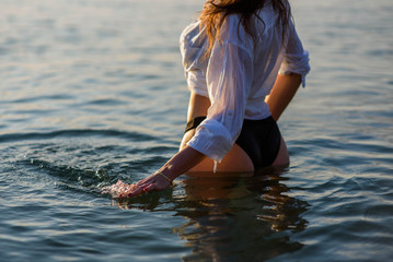 Young fit woman in a white shirt and bikini in the sea