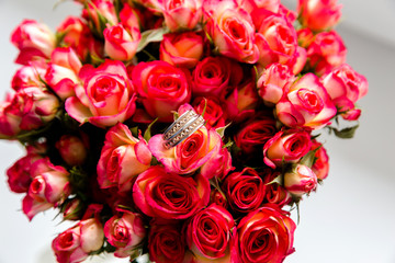 A pair of wedding rings on a bouquet of red flowers, close up shot