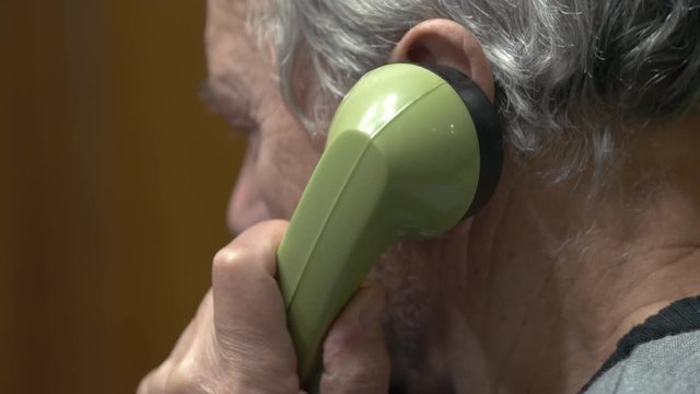 An Elderly Man Talking On A Landline Phone