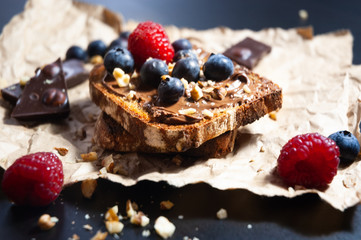  Delicious chocolate bread toast with chocolate spread and bluberry and nuts toppings on rustic paper with black background