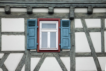 Old ancient wooden window with blinds or shutters. Scenic original and colorful view of antique windows in old city Sindelfingen, Germany. Isolated on wall. No people. Front view. Old fashioned style. - 243027479
