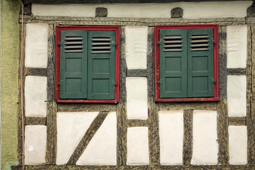Old ancient wooden window with blinds or shutters. Scenic original and colorful view of antique windows in old city Sindelfingen, Germany. Isolated on wall. No people. Front view. Old fashioned style. - 243027820