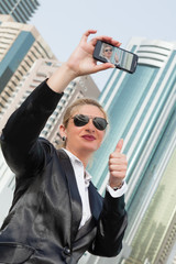 Businesswoman taking a self portrait photo, selfie,  on the street, city scape Dubai in the background