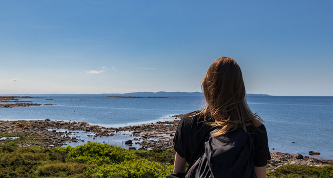 Woman standing and looking at the ocean on Hallands Vadero island in southern Sweden during summer. 