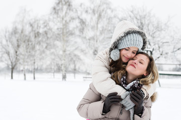 Fototapeta na wymiar Mother and daughter hugging outdoors in the wintry landscape.Copy space