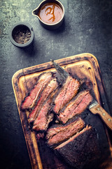 Traditional smoked barbecue wagyu beef brisket as piece and sliced offered as top view on an old...