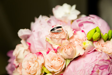A pair of wedding gold rings on a bouquet of pink flowers, close up shot