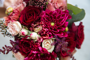 A pair of wedding gold rings on a bouquet of colorful flowers, close up shot