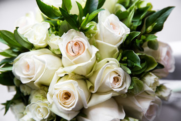 Fototapeta na wymiar A pair of wedding rings on a bouquet of white roses, close up shot