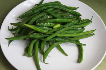 Boiled beans pods  with salt on a   plate.  Candid.