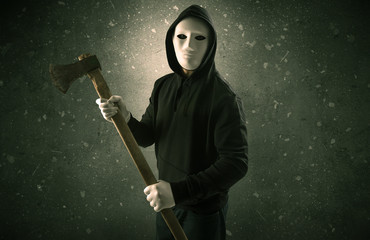 Masked armed villain in empty dark room with gun ax chainsaw mallet wrench
