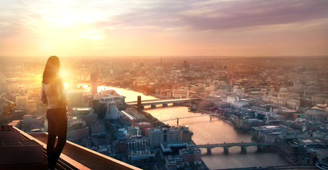 Young woman looking at the City of London at sunset. Planning the future, life and joy concept.