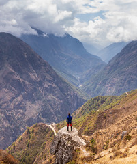 Fototapeta na wymiar Person standing on a rock looking out over a valley in Nepal during the Everest Base Camp Trek.