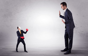 Big businessman being afraid of small masked businessman with box gloves in an empty room concept
