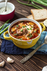 Traditional Ukrainian borsch with meat. Plate of red beetroot soup on rustic background. Traditional Ukraine food cuisine