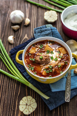Traditional Ukrainian borsch with meat. Plate of red beetroot soup on rustic background. Traditional Ukraine food cuisine