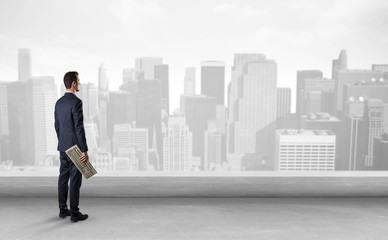 Businessman standing with his back on a roof with objects in his hand
