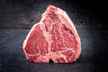 Traditional raw dry aged wagyu porterhouse steak as closeup on an old rustic board
