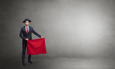 Businessman standing with red toreador cloth in his hand in an empty room
