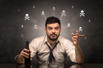 Loser drunk man sitting at table with skulls concept around
