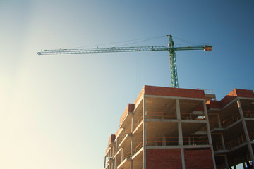 Naklejka premium Industrial crane at the construction site against the blue sky.