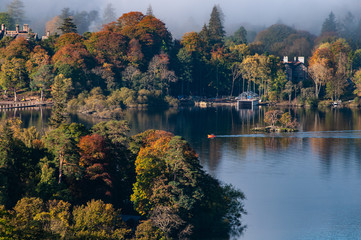 Fototapeta premium The cloud over Derwent Water lake in the Lake District Cumbria with Autumn colours and view of boathouse in the clear water.