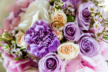 A pair of wedding gold rings on a bouquet of colorful flowers, close up shot