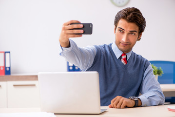 Young handsome employee working in the office 