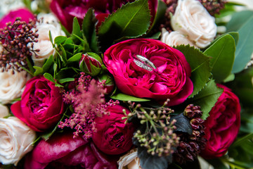 A pair of wedding rings on a bouquet of colorful flowers, close up shot