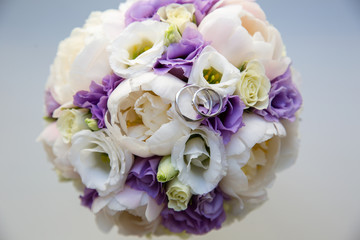 A pair of wedding rings on a bouquet of colorful flowers, close up shot