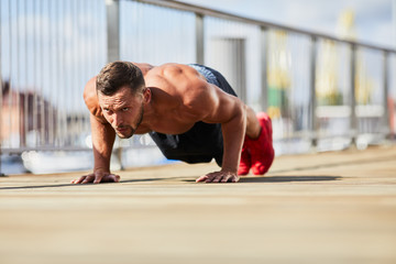 Fototapeta premium Athletic man doing pushup exercise outdoors