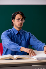 Young male teacher in front of chalkboard  