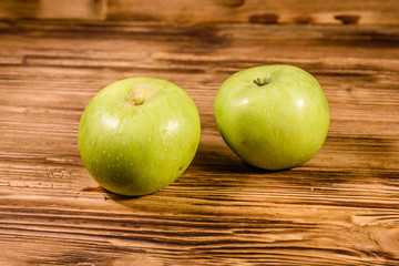 Two ripe green apples on a wooden table
