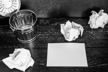 garbage bin on desk setting with empty notepad and scrunched paper balls