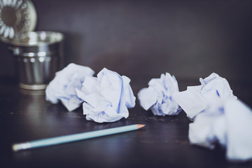 garbage bin on desk setting with pencil and scrunched paper balls