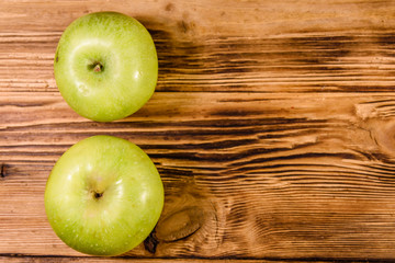 Two ripe green apples on a wooden table. Top view